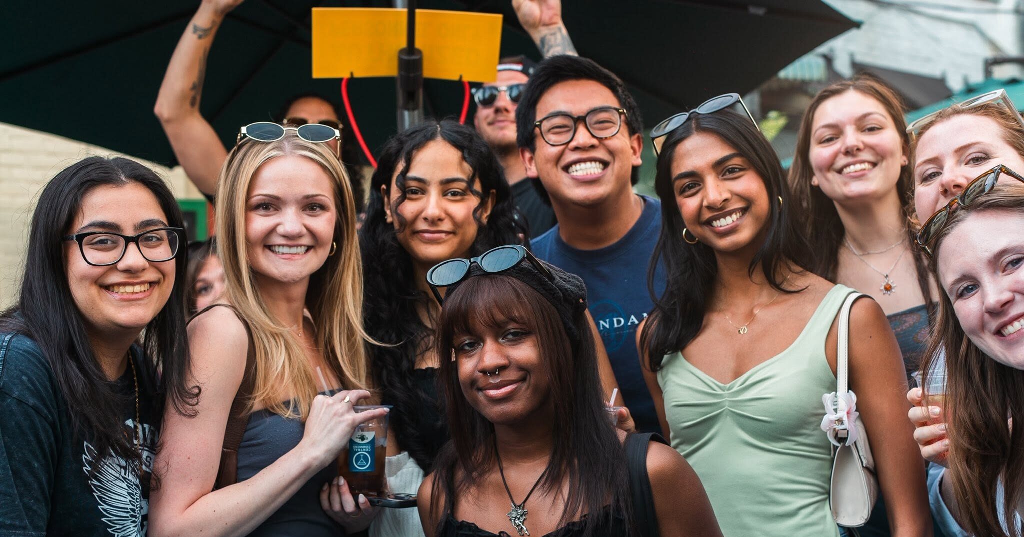  A group of young adults gathered together, and smiling at camera.